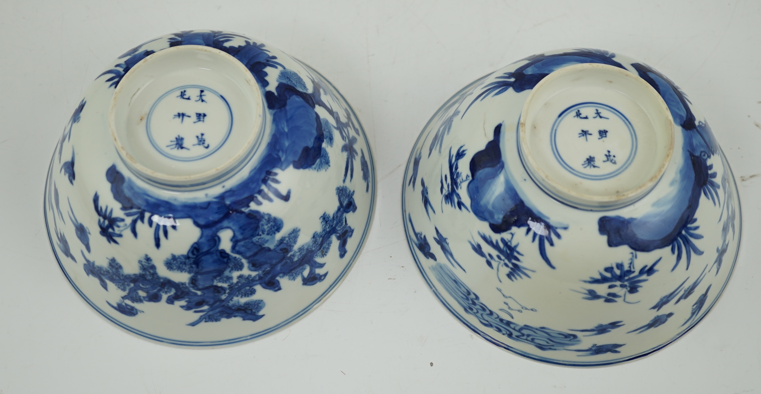 A near pair of Chinese blue and white ‘birds’ bowls, Kangxi period, one bowl restored